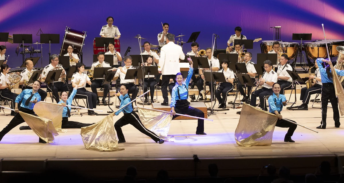 ステージで演奏する警視庁音楽隊とカラーガードの演出（過去の演奏の様子）